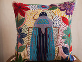 Coussin brode main avec des motifs insectes et fleur, commerce equitable.